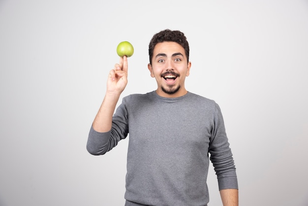 Jovem feliz segurando maçã verde.