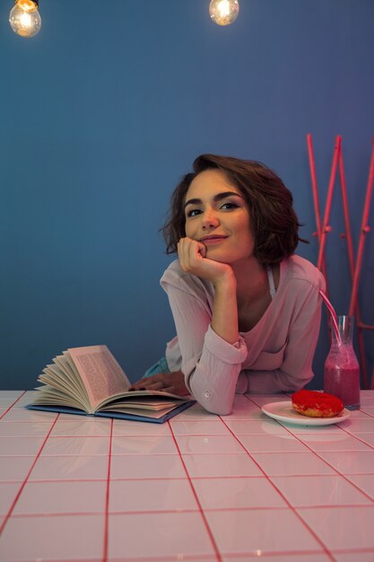 Jovem feliz sentado à mesa com um livro