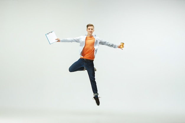 Foto grátis jovem feliz trabalhando no escritório, pulando e dançando com roupas casuais ou terno isolado no fundo branco.