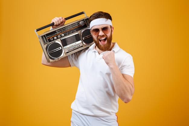 Foto grátis jovem feliz usando óculos escuros, segurando o gravador