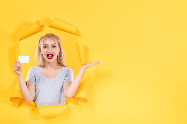 Foto grátis jovem fêmea com cartão de crédito em compras de venda de dinheiro facial de fundo amarelo