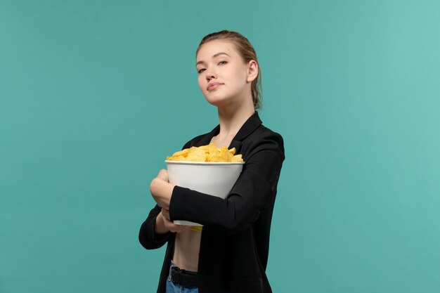 Foto grátis jovem fêmea comendo batata frita assistindo filme na superfície azul