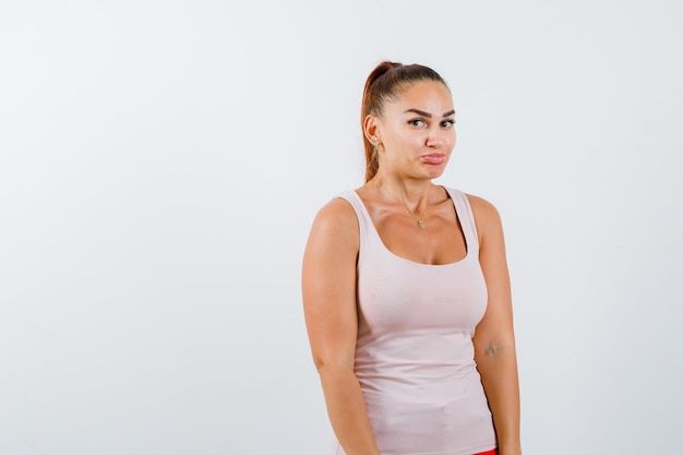 Jovem fêmea curvando os lábios na camiseta e parecendo hesitante, vista frontal.