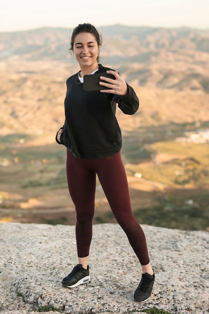 Jovem fêmea na montanha tomando selfie