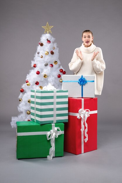 jovem fêmea perto de presentes de natal no chão cinza