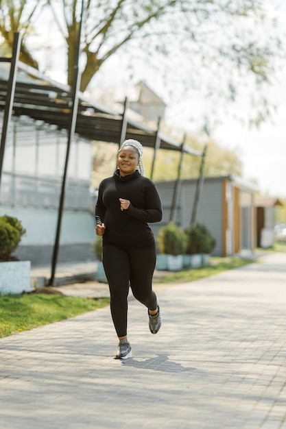 Jovem fêmea se divertindo treinando ao ar livre. Conceito de estilo de vida de pessoas desportivas. Mulher em roupas esportivas correndo