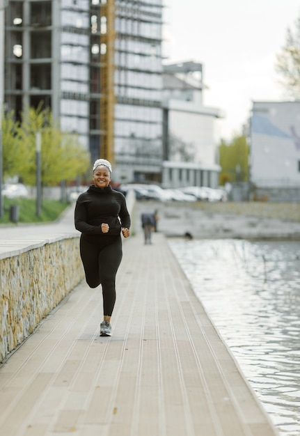 Jovem fêmea se divertindo treinando ao ar livre. conceito de estilo de vida de pessoas desportivas. mulher em roupas esportivas correndo