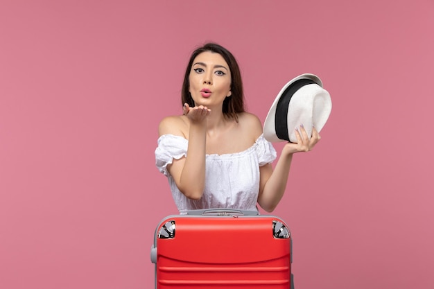 Jovem fêmea se preparando para as férias enviando beijos no ar na viagem fundo rosa