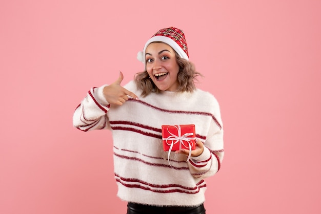 Jovem fêmea segurando o pequeno presente de natal rosa