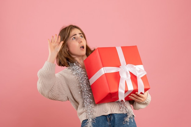 jovem fêmea segurando o presente de Natal nas mãos na rosa