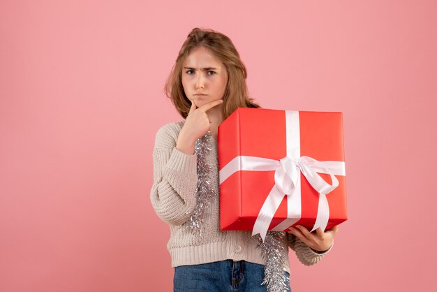 jovem fêmea segurando o presente de Natal nas mãos na rosa