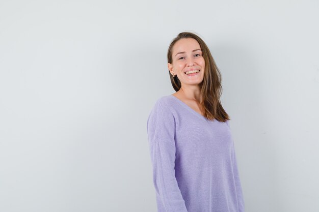 Jovem fêmea sorrindo na blusa lilás e olhando positiva. vista frontal. espaço para texto