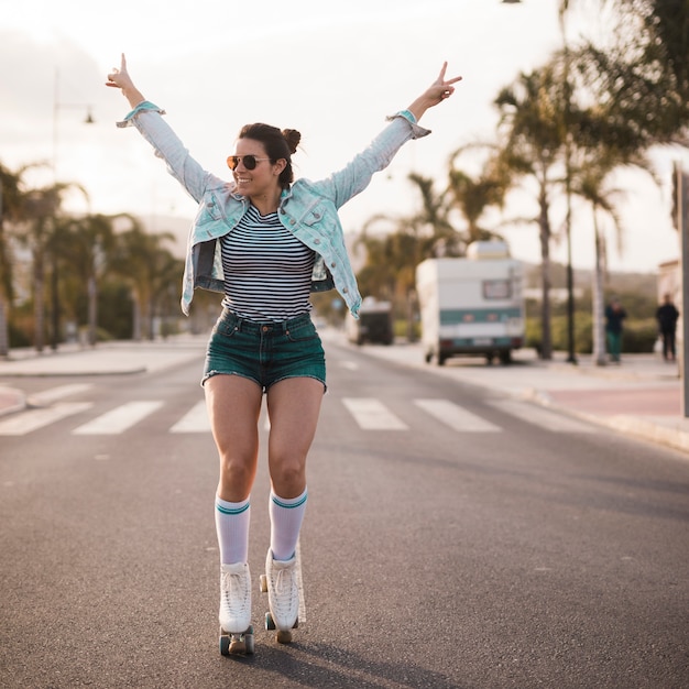 Jovem, femininas, skater, levantamento, dela, braços, fazendo, gesto paz, equilibrar, ligado, estrada