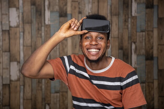 Foto grátis jovem fica animado com o telefone enquanto o segura contra a cabeça