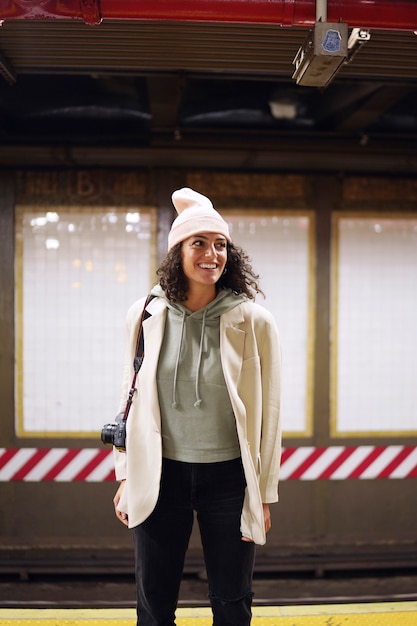 Jovem fotógrafa estilosa explorando o metrô da cidade