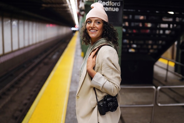 Jovem fotógrafa estilosa explorando o metrô da cidade