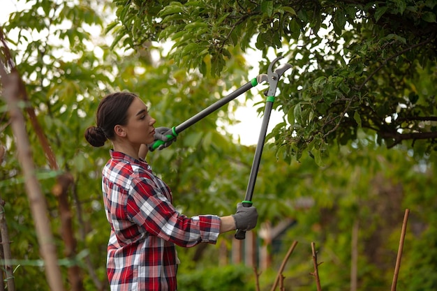 Jovem gadener cortando galhos na árvore cuidando Conceito de jardim de hobby da natureza