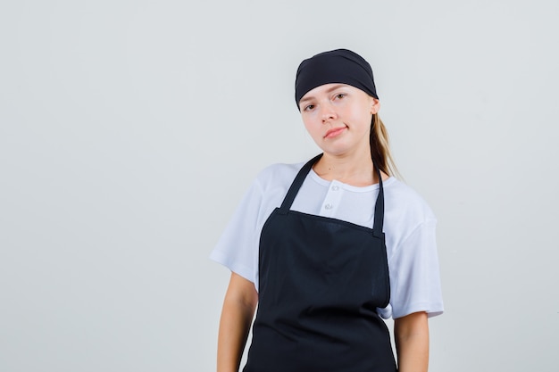 Jovem garçonete parecendo de uniforme e avental e parecendo descontente