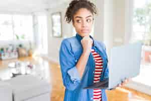 Foto grátis jovem garota afro-americana de pé trabalhando usando laptop rosto sério pensando sobre a pergunta ideia muito confusa