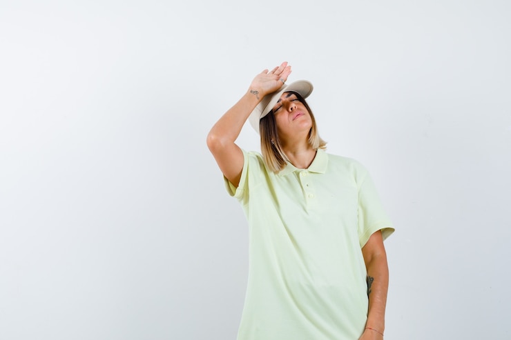 Foto grátis jovem garota em t-shirt e boné segurando a mão na testa, mantendo os olhos fechados e parecendo exausta, vista frontal.