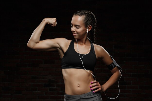 Jovem garota esportiva bonita sorrindo, posando, isolado na parede preta