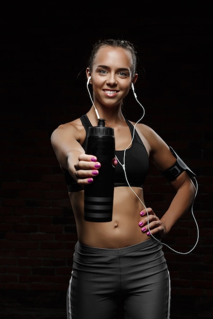 Foto grátis jovem garota esportiva bonita sorrindo, posando, isolado na parede preta