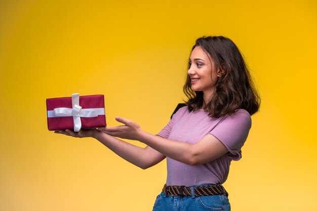 Jovem garota segurando uma caixa de presente em seu aniversário e parece feliz.