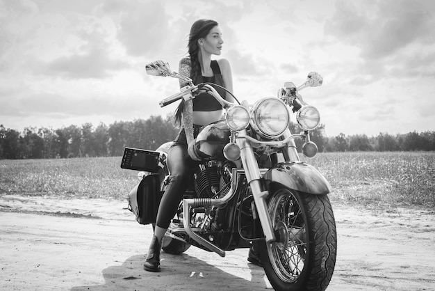 Jovem garota sexy, posando de motocicleta ao pôr do sol. conceito de esporte a motor. mídia mista