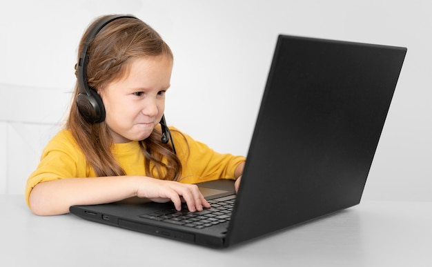 Jovem garota usando laptop com fones de ouvido