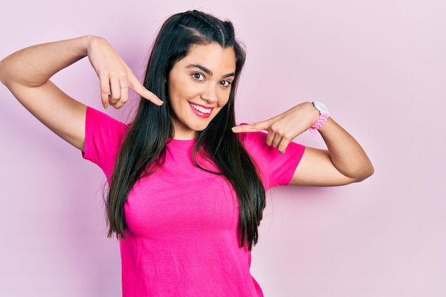 Jovem hispânica vestindo camiseta rosa casual sorrindo alegre mostrando e apontando com os dedos, dentes e boca. conceito de saúde bucal.