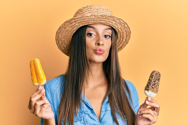 Foto grátis jovem hispânica vestindo estilo de verão segurando sorvete olhando para a câmera mandando um beijo sendo adorável e sexy expressão de amor