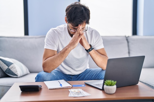 Jovem hispânico estressado usando laptop trabalhando em casa