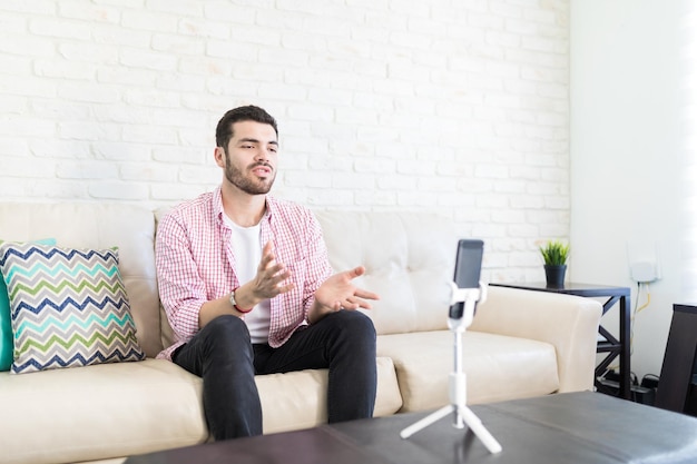 Jovem hispânico fazendo blog de vídeo no smartphone em casa