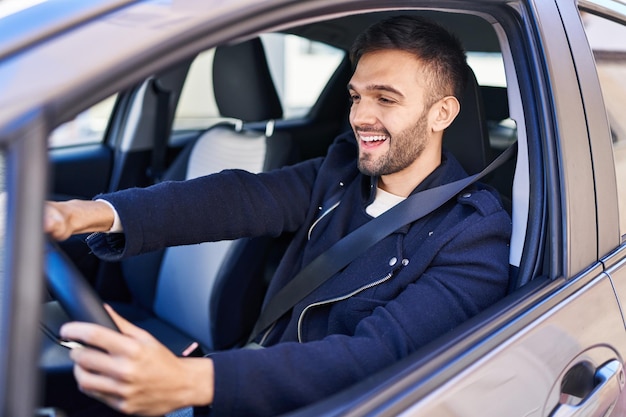 Foto grátis jovem hispânico sorrindo confiante dirigindo carro na rua