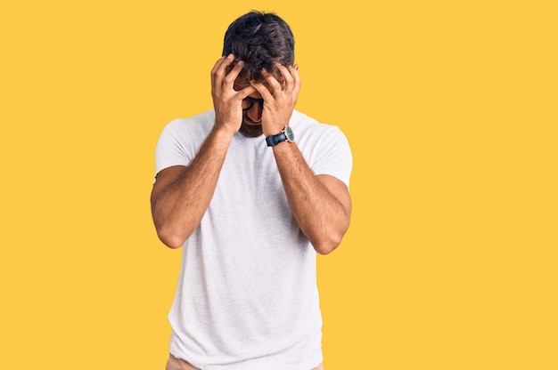 Foto grátis jovem hispânico vestindo roupas casuais e óculos sofrendo de dor de cabeça desesperado e estressado porque dor e enxaqueca. mãos na cabeça.