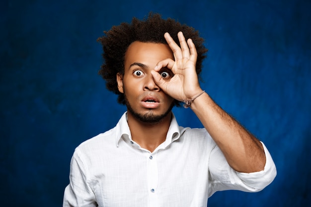 Jovem homem Africano bonito posando sobre parede azul.