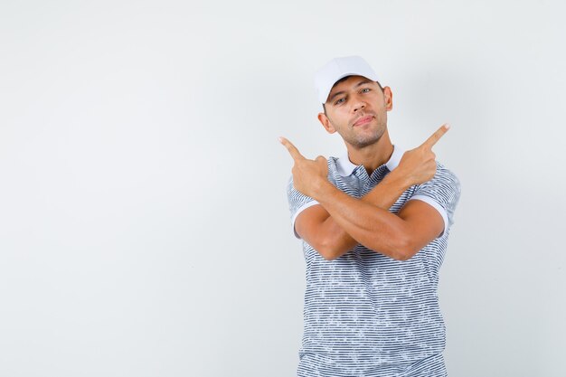 Jovem homem apontando para o outro lado com camiseta e boné e parecendo confiante