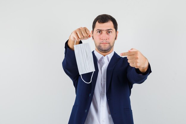 Jovem homem apontando para uma máscara médica na camisa