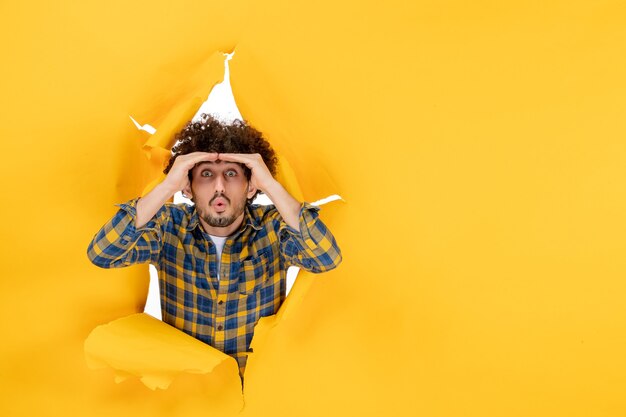 Foto grátis jovem homem com cabelo encaracolado em um fundo amarelo rasgado de frente