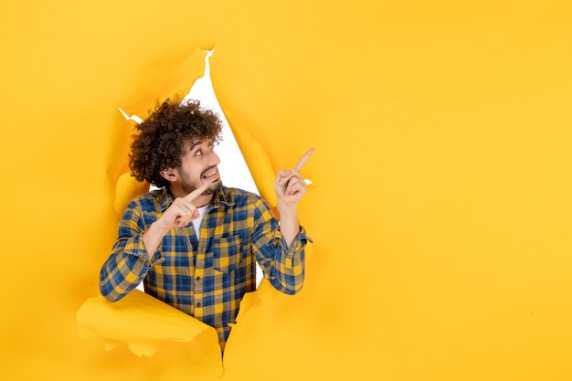 Foto grátis jovem homem com cabelo encaracolado em um fundo amarelo rasgado de frente