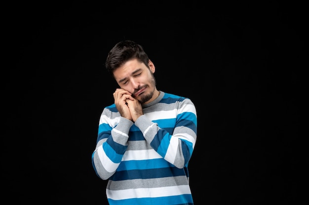 Jovem homem com camisa listrada azul, de frente, triste e chorando