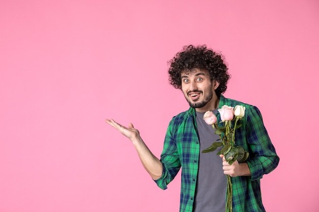 Jovem homem com rosas cor de rosa na frente