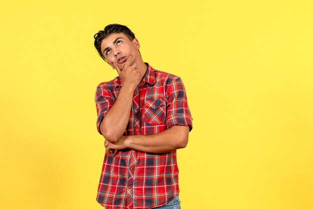 Jovem homem de camisa brilhante, de frente, pensando no modelo masculino de cor de fundo amarelo