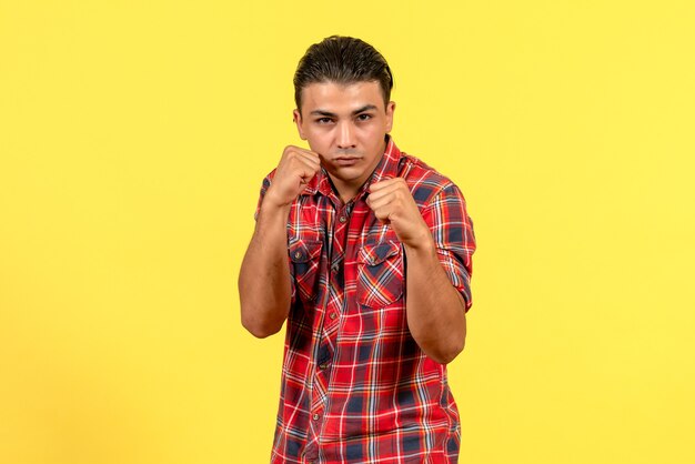 Jovem homem de camisa brilhante, de frente, posando em modelo masculino de cor de fundo amarelo