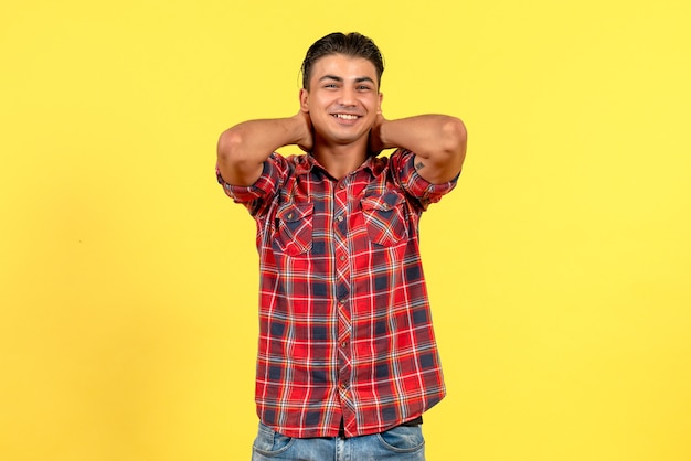 Jovem homem de camisa brilhante sorrindo de frente para o modelo masculino de cor de fundo amarelo