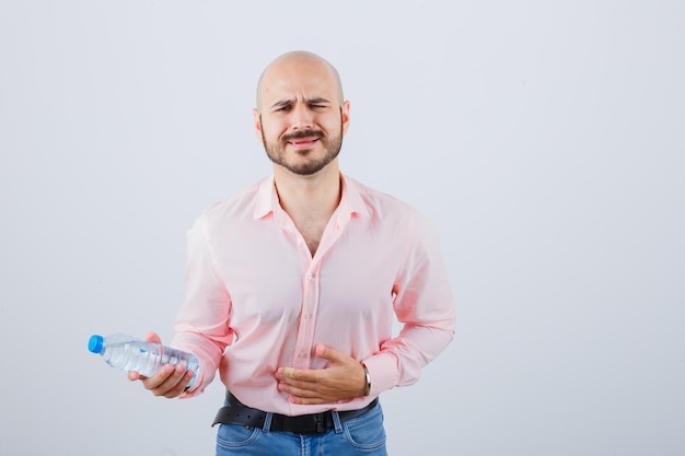 Jovem homem de camisa, jeans, sentindo-se nauseado e parecendo indisposto, vista frontal.