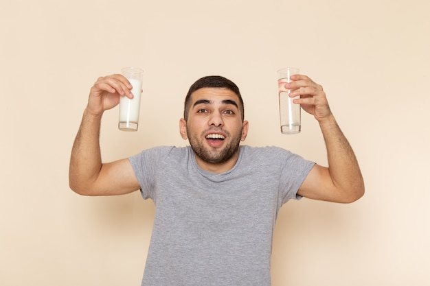 Jovem homem de camiseta cinza segurando um copo de água com leite na frente