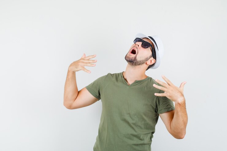 Foto grátis jovem homem de camiseta e chapéu verdes sentindo calor e parecendo preocupado