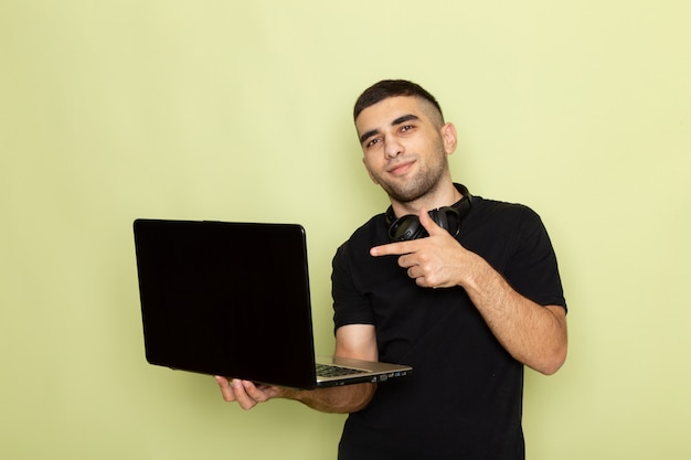 Jovem homem de camiseta preta sorrindo e usando laptop na frente