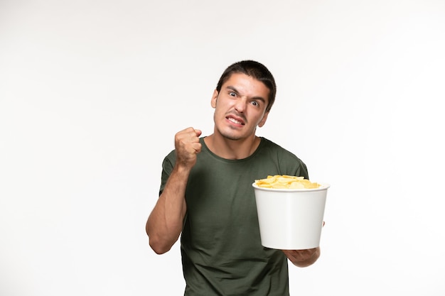 Jovem homem de camiseta verde segurando batata cips na parede branca-clara filme solitário cinema pessoa